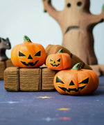 The Bumbu Toys Halloween Pumpkins Set placed in a small world play scvene with other wooden Bumbu toys including hay bales and a spooky tree in the background. 