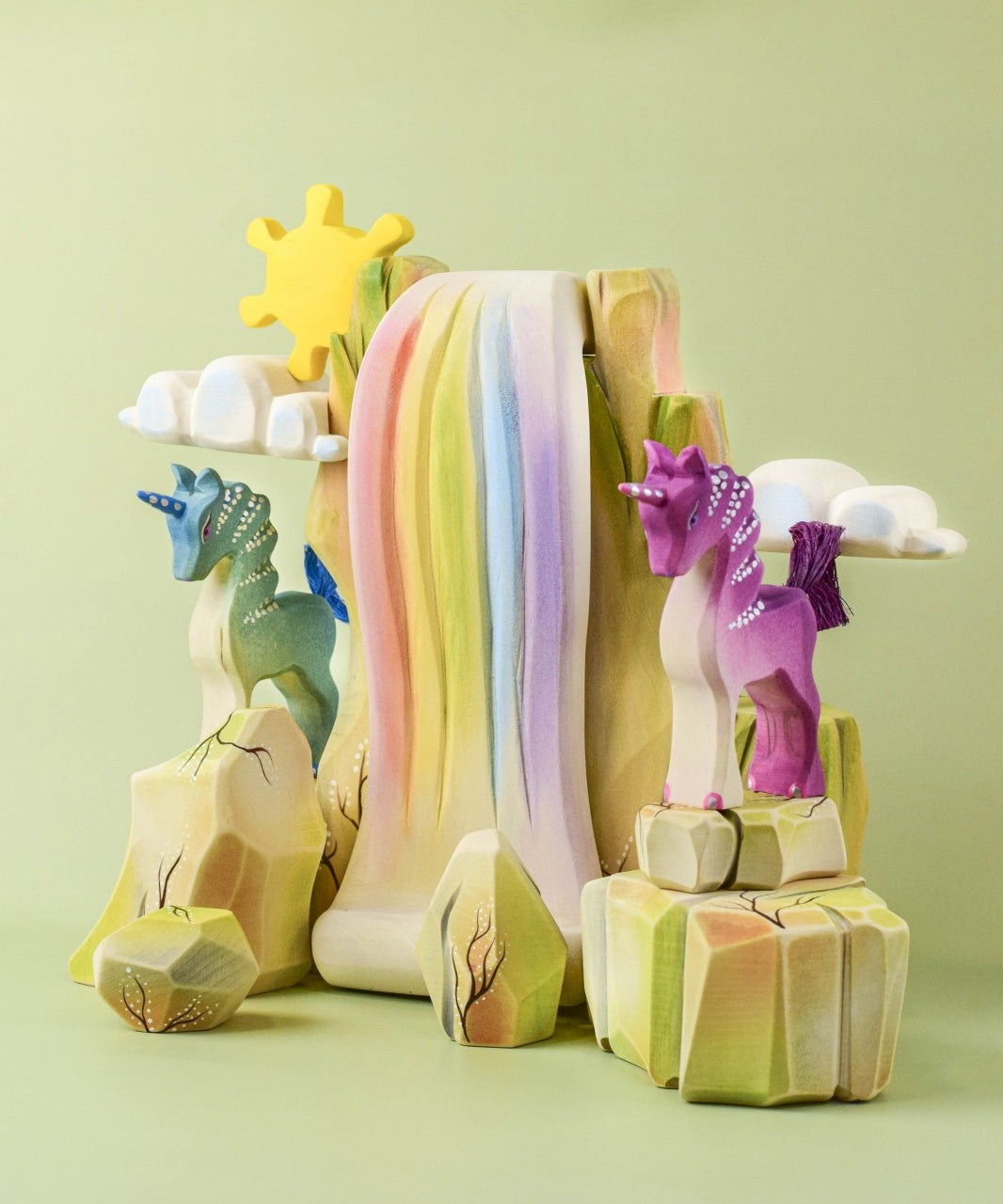 The Bumbu Toys Rainbow waterfall and Rainbow Rocks shown in a small world play scene alongside Bumbu unicorns. 