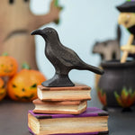 The Bumbu Toys Raven placed on a pile of wooden Bumbu books at the front and centre of a Halloween themed small world play set up. 