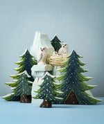 Two Bumbu Toys Snowy owls with three chicks placed in a next on top of the Bumbu icy cliffs with the snowy trees next to them. 