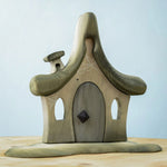 Bumbu Toys Witches house decorated with a Halloween theme. The house is grey in colour hand has cobwebs and a spider painted on. The House is placed on a wooden surface.