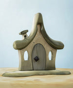 Bumbu Toys Witches house decorated with a Halloween theme. The house is grey in colour hand has cobwebs and a spider painted on. The House is placed on a wooden surface.