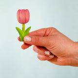 Adult hand holding the Bumbu handcrafted wooden pink tulip decorative figure showing size