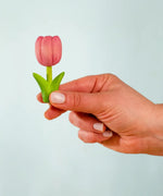 Adult hand holding the Bumbu handcrafted wooden pink tulip decorative figure showing size