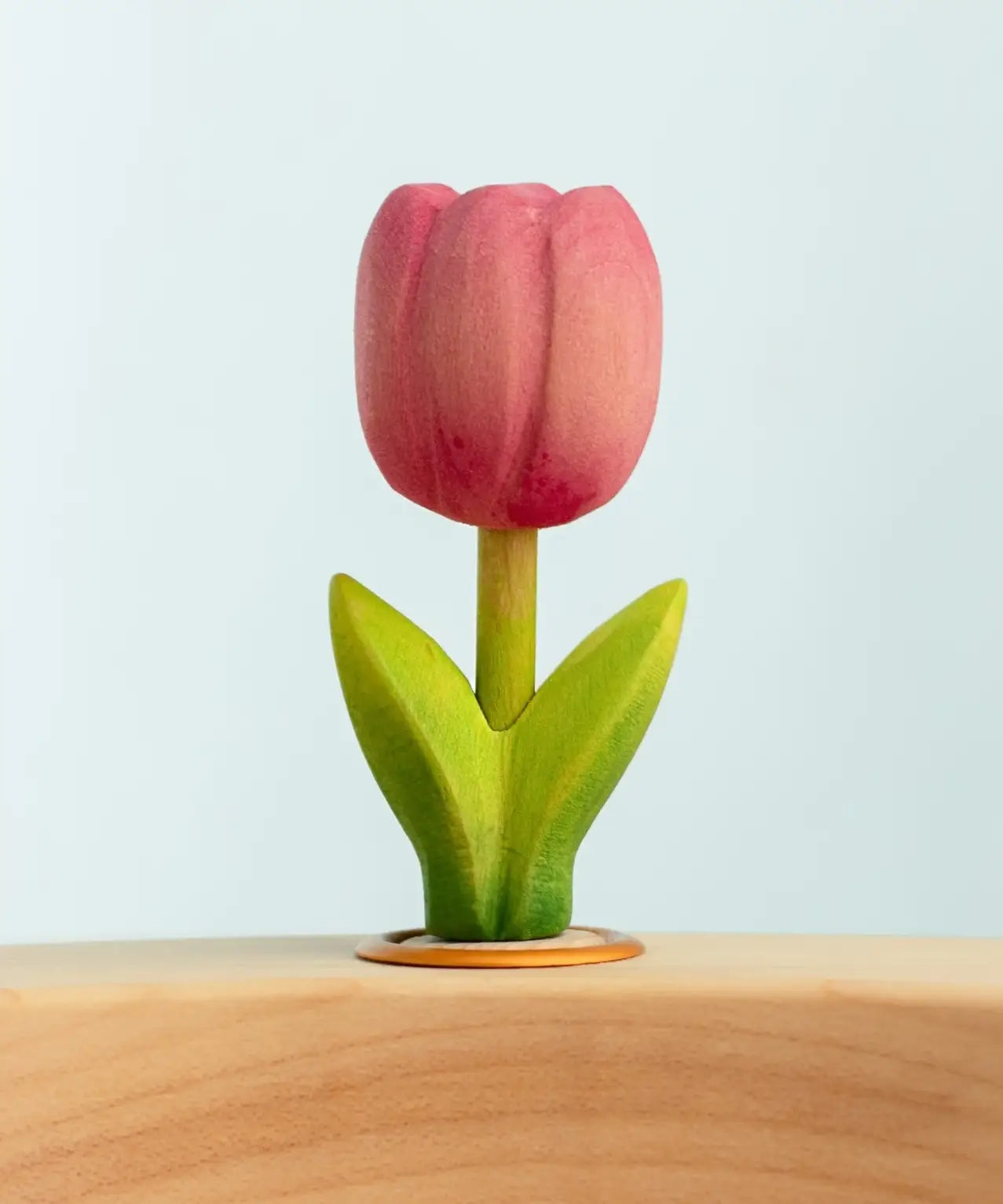 Bumbu wooden hand painted pink festive tulip decorative figure standing in a celebration ring against a blue background