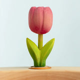 Bumbu wooden hand painted pink festive tulip decorative figure standing in a celebration ring against a blue background