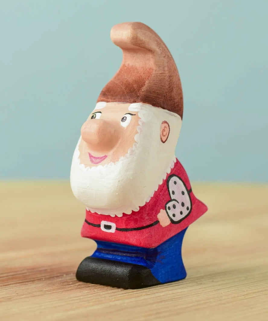 The Bumbu Toys Whittle Dwarf has a red coloured top, blue trousers, a brown hat and a white beard.