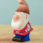 The Bumbu Toys Whittle Dwarf has a red coloured top, blue trousers, a brown hat and a white beard.