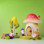 The Bumbu wooden toy dwarves shown in a small world play scene next to the Bumbu Toadstool house, flowers and birch tree. 
