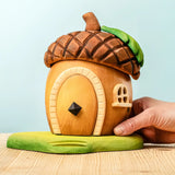 Adult hand holding the Bumbu toys handcrafted wooden acorn house showing scale