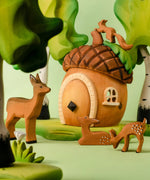 A playscene showing a Bumbu toys acorn house, deer and squirrel figures and trees in the background.