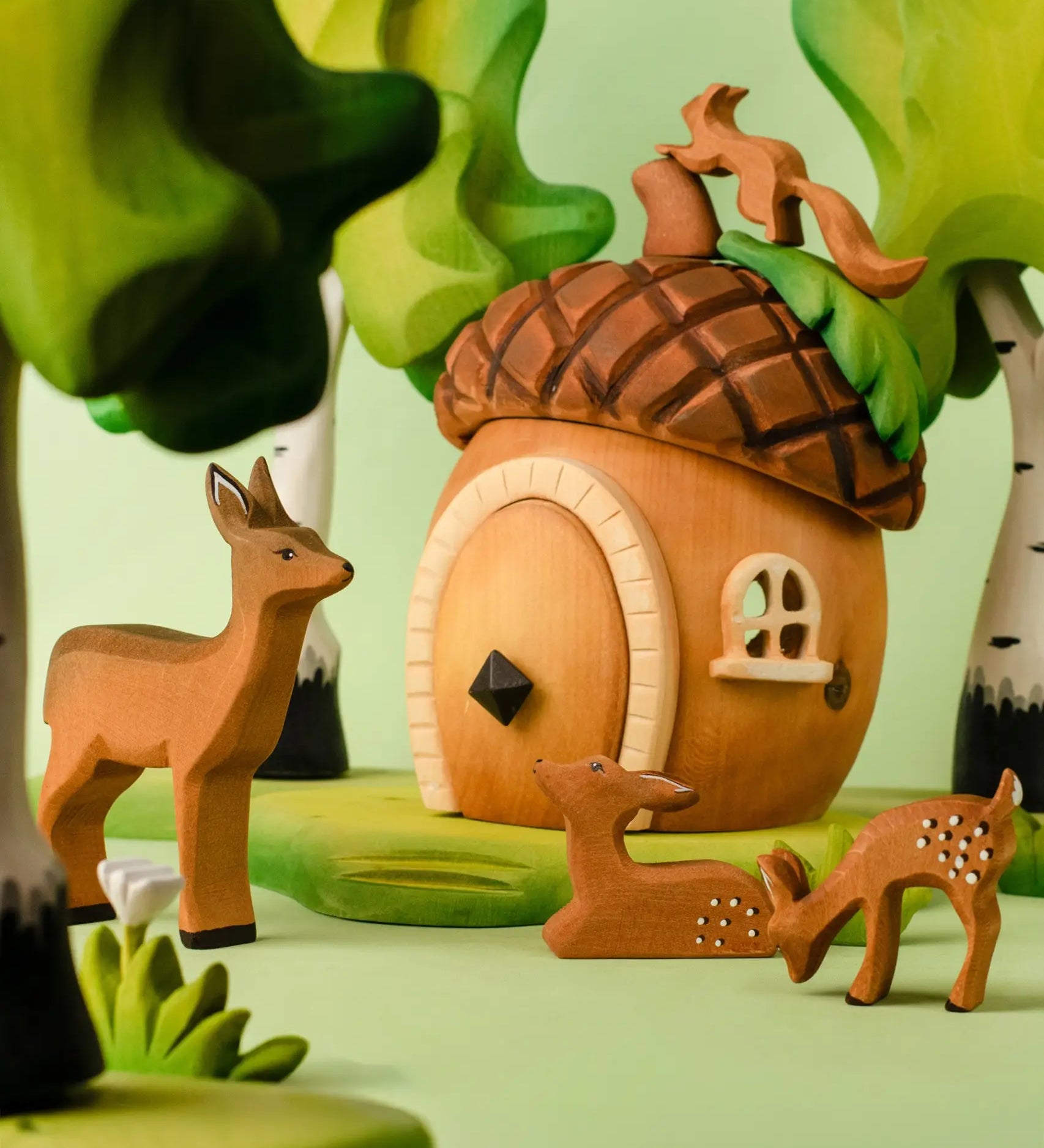 A playscene showing a Bumbu toys acorn house, deer and squirrel figures and trees in the background.