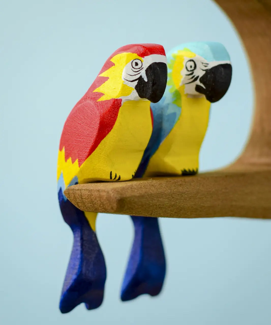 Bumbu toys handcrafted wooden  Amazonian parrot and a blue macaw perched on a branch