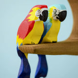 Bumbu toys handcrafted wooden  Amazonian parrot and a blue macaw perched on a branch