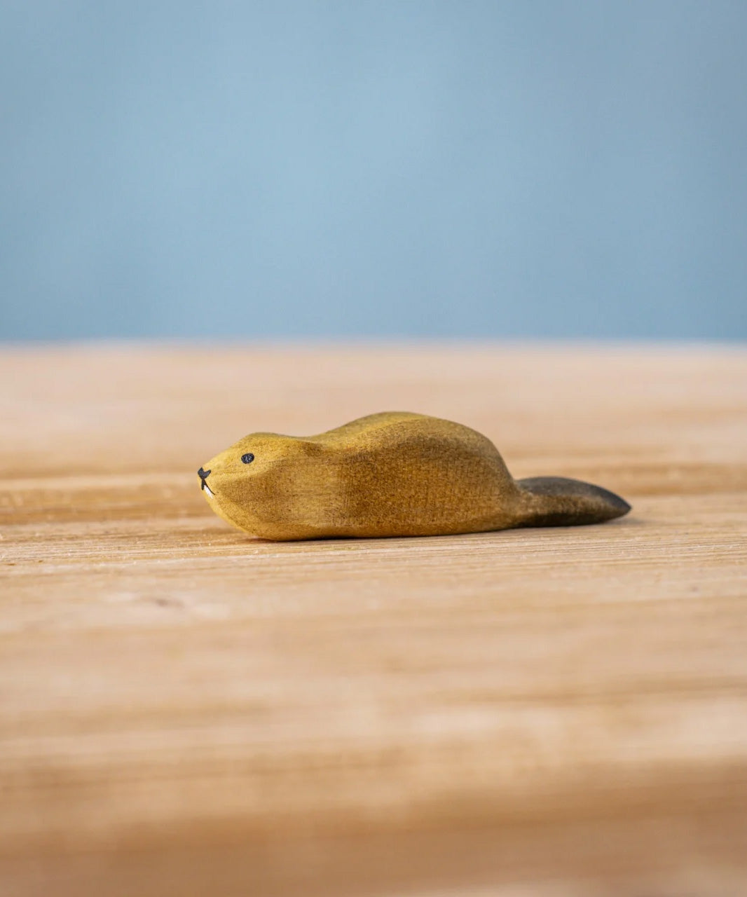 Bumbu wooden baby beaver figure resting on a wooden board.