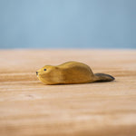 Bumbu wooden baby beaver figure resting on a wooden board.