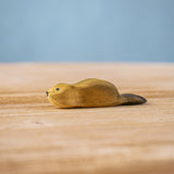 Bumbu wooden baby beaver figure resting on a wooden board.