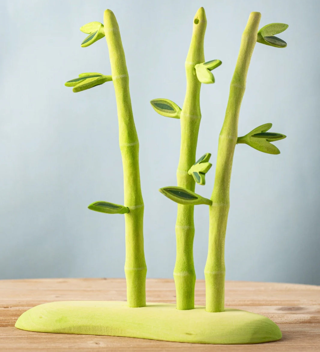 A Bumbu wooden bamboo set on a green base, features detachable leaves.
