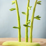 A Bumbu wooden bamboo set on a green base, features detachable leaves.