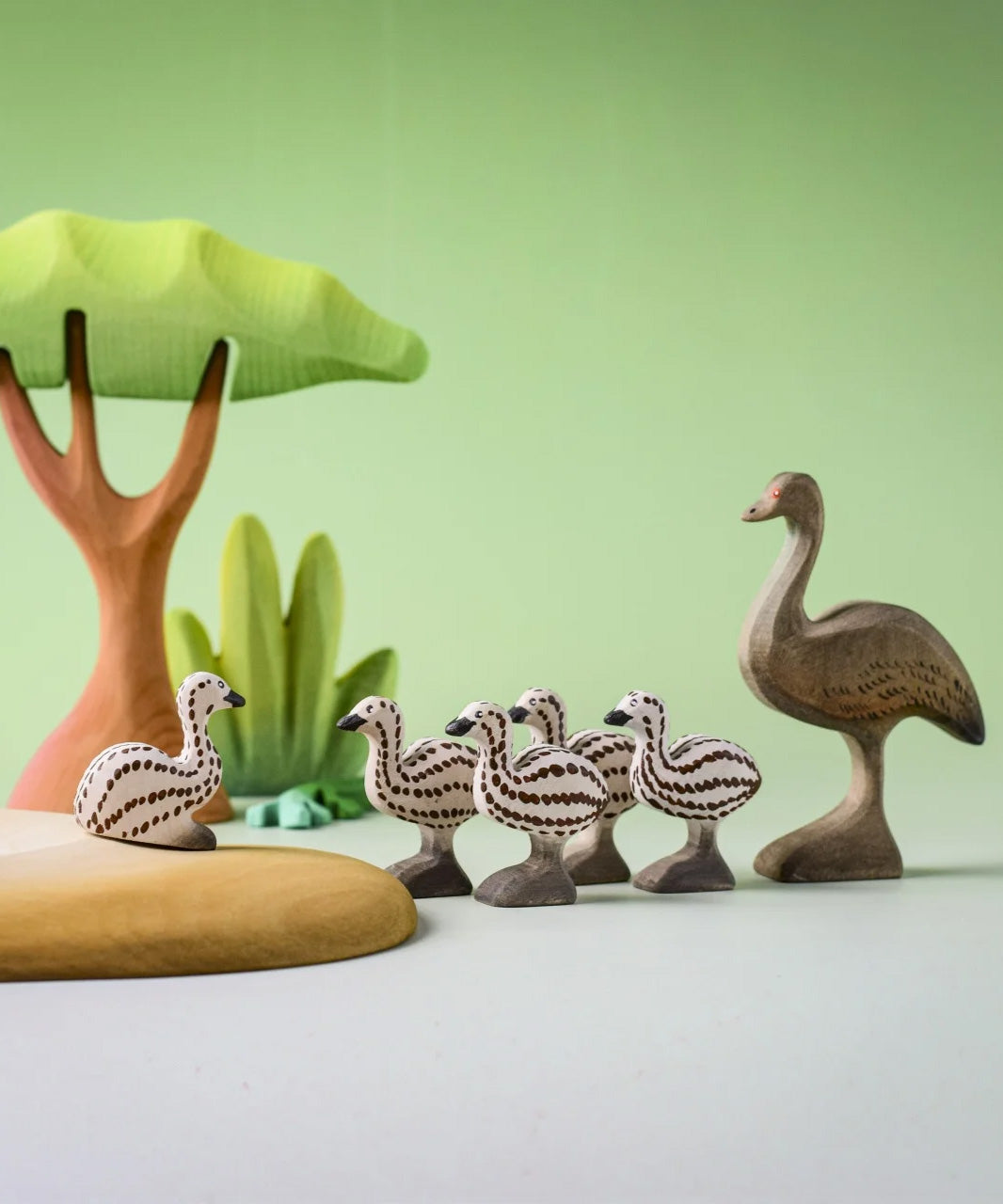 A play scene featuring the Bumbu wooden female emu standing next to emu chicks and a sitting emu chick