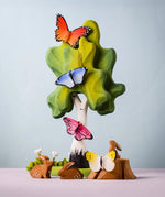 Bumbu Toys wooden Butterflies, placed on a Bumbu Birch Tree surrounded by Bumbu Rabbits, flowers and grass.