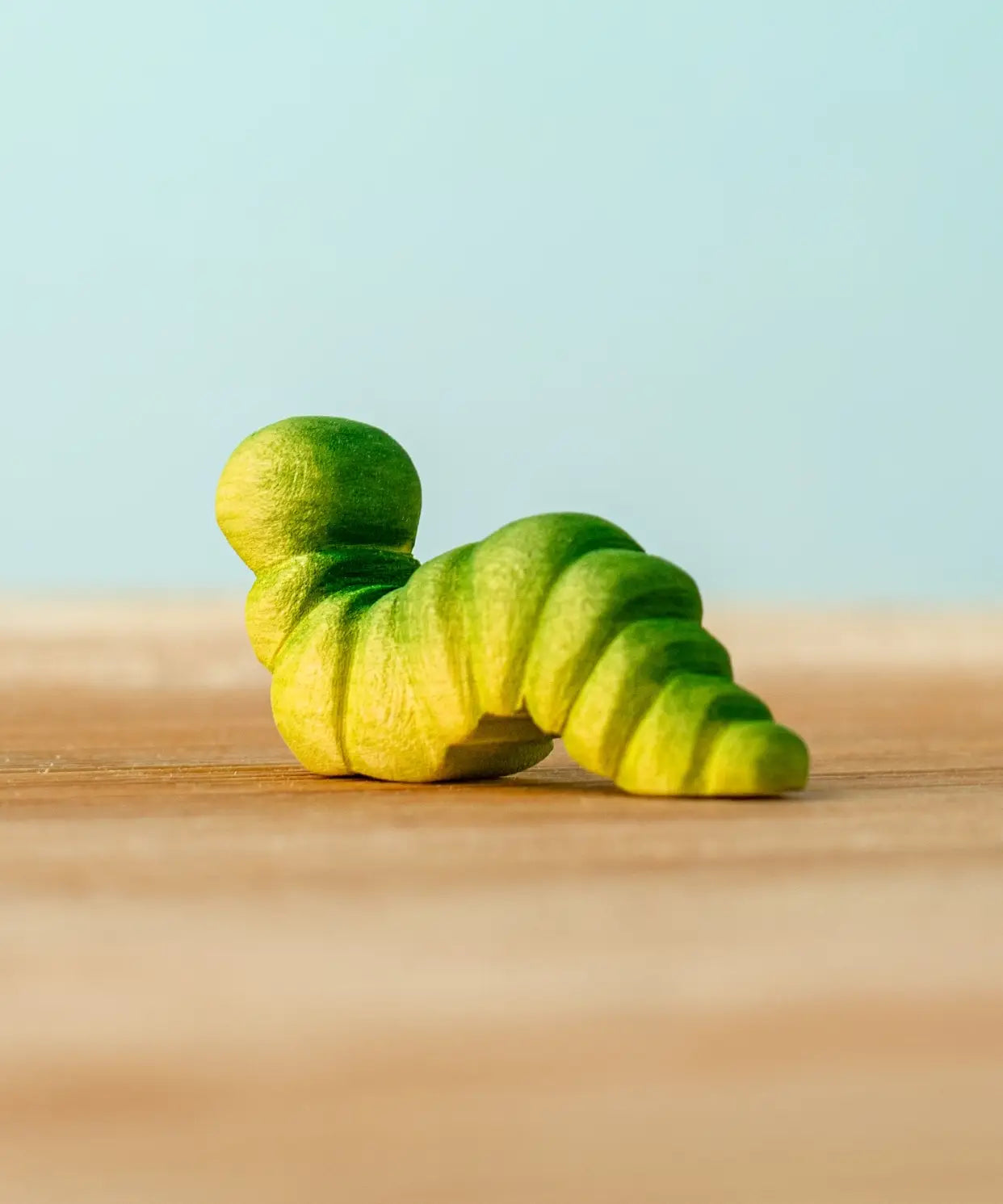 Back of a Bumbu handcrafted wooden green caterpillar figure 