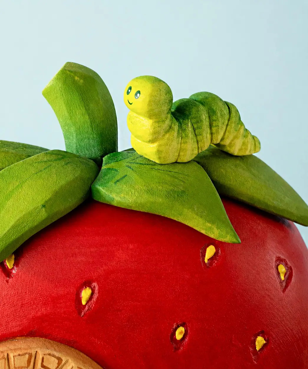 Bumbu handcrafted wooden green caterpillar figure on top of a strawberry house set