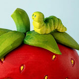Bumbu handcrafted wooden green caterpillar figure on top of a strawberry house set