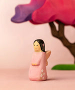 Bumbu handcrafted wooden cherry fairy figure in front of a pink blossom tree