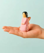 Adult hand holding a Bumbu handcrafted wooden cherry fairy figure showing scale