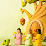 Bumbu handcrafted wooden cherry, sage and golden fairy figures in front of a treehouse