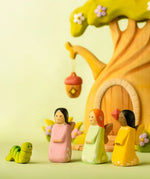 Bumbu handcrafted wooden cherry, sage and golden fairy figures in front of a treehouse