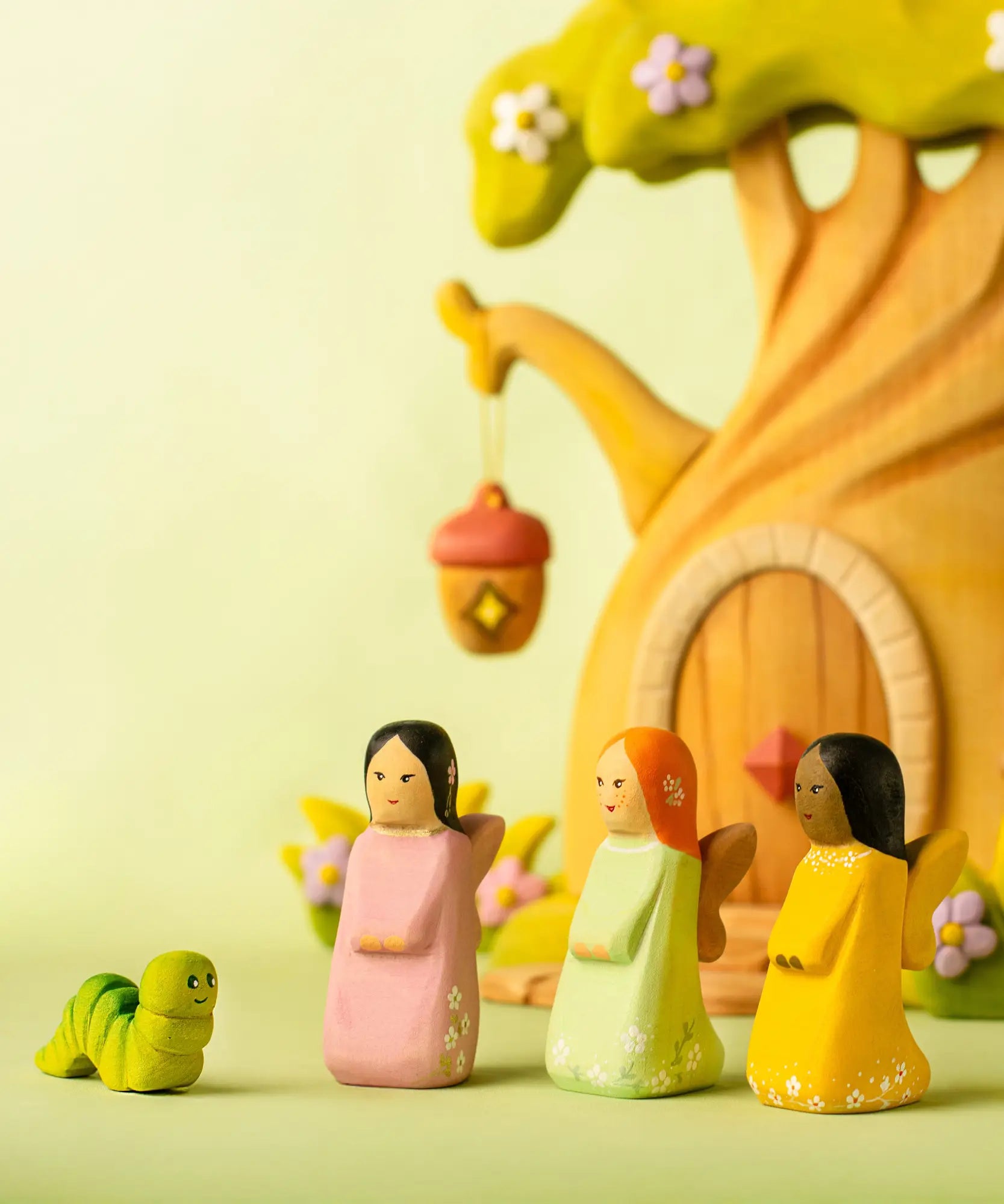 Bumbu handcrafted wooden cherry, sage and golden fairy figures in front of a treehouse
