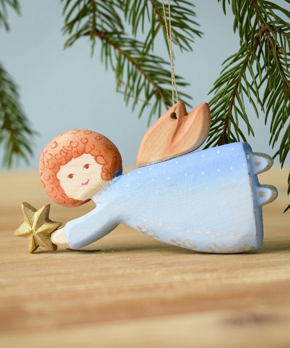 A Bumbu Christmas Angel placed on a wooden surface. 