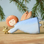A Bumbu Christmas Angel placed on a wooden surface. 