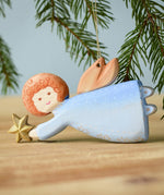 A Bumbu Christmas Angel placed on a wooden surface. 