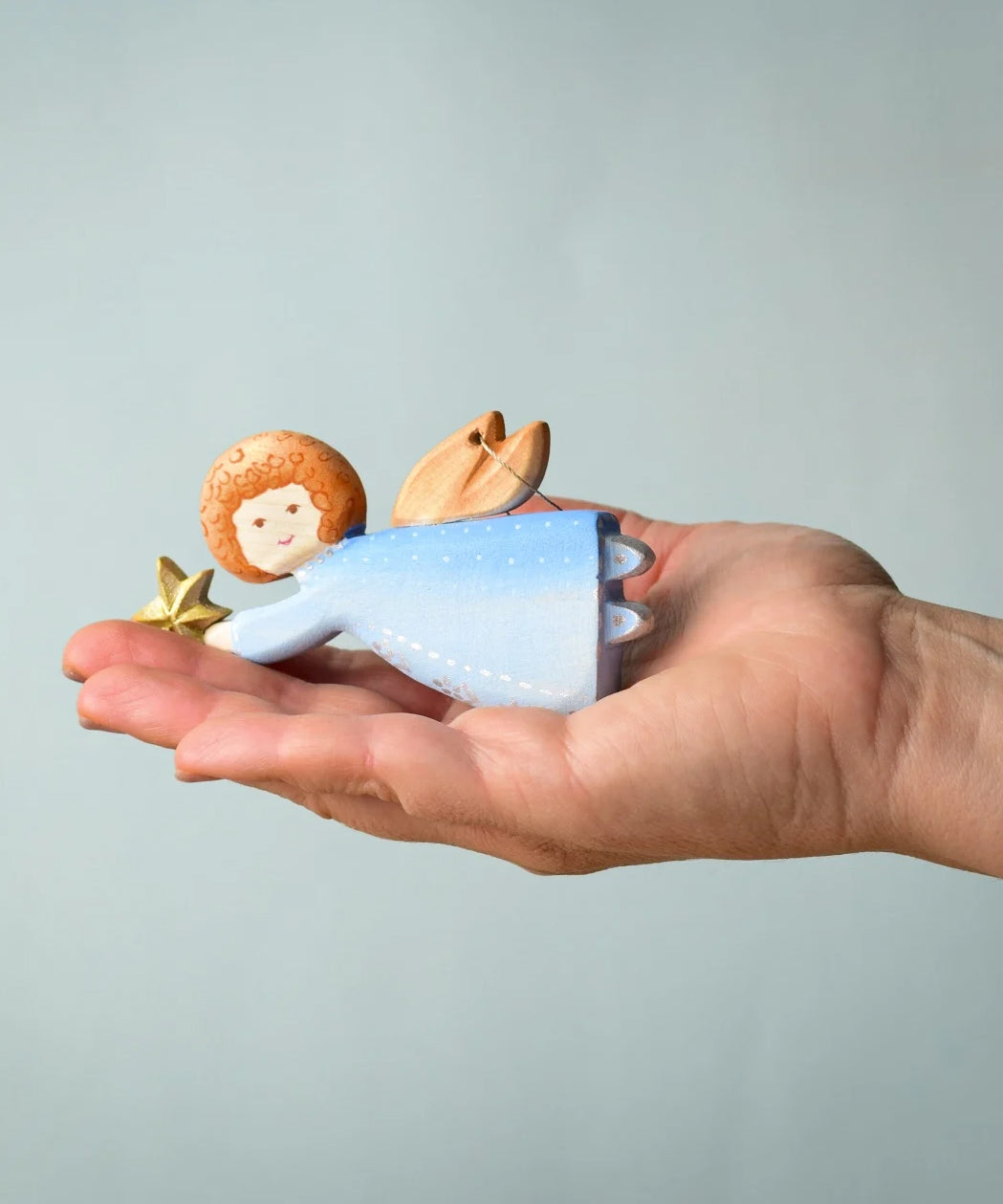 A Bumbu Christmas Angel placed in the palm of an adult's hand. 