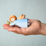 A Bumbu Christmas Angel placed in the palm of an adult's hand. 