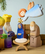 A Bumbu Christmas angel hanging above a festive small world play scene. 