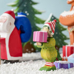 A Christmas scene including the Bumbu Santas elf holding a present, the Bumbu Santa and Christmas trees