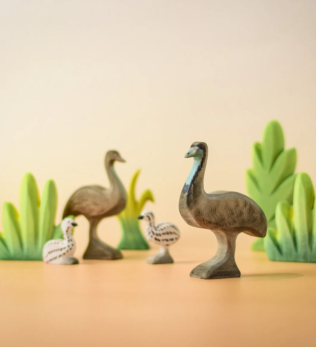 A family of Bumbu wooden emu's standing next to Bumbu decorative bushes.