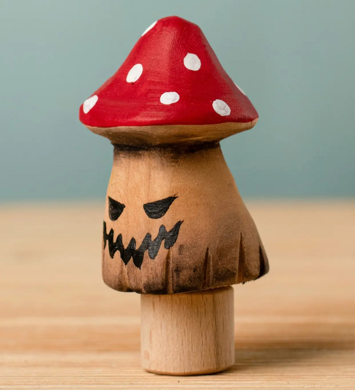Bumbu handcrafted wooden enchanted mushroom decorative figure with painted spooky facial features and a red with white spots cap