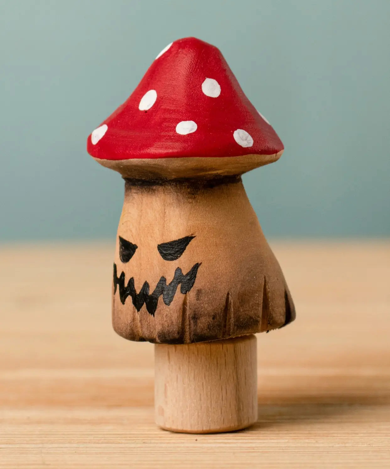 Bumbu handcrafted wooden enchanted mushroom decorative figure with painted spooky facial features and a red with white spots cap