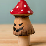 Bumbu handcrafted wooden enchanted mushroom decorative figure with painted spooky facial features and a red with white spots cap