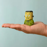 Bumbu handcrafted wooden Frankenstein halloween decorative figure standing on a adult hand showing scale