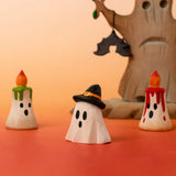 A Bumbu wooden ghost wizard decorative figure standing in front of spooky candles and tree figures 