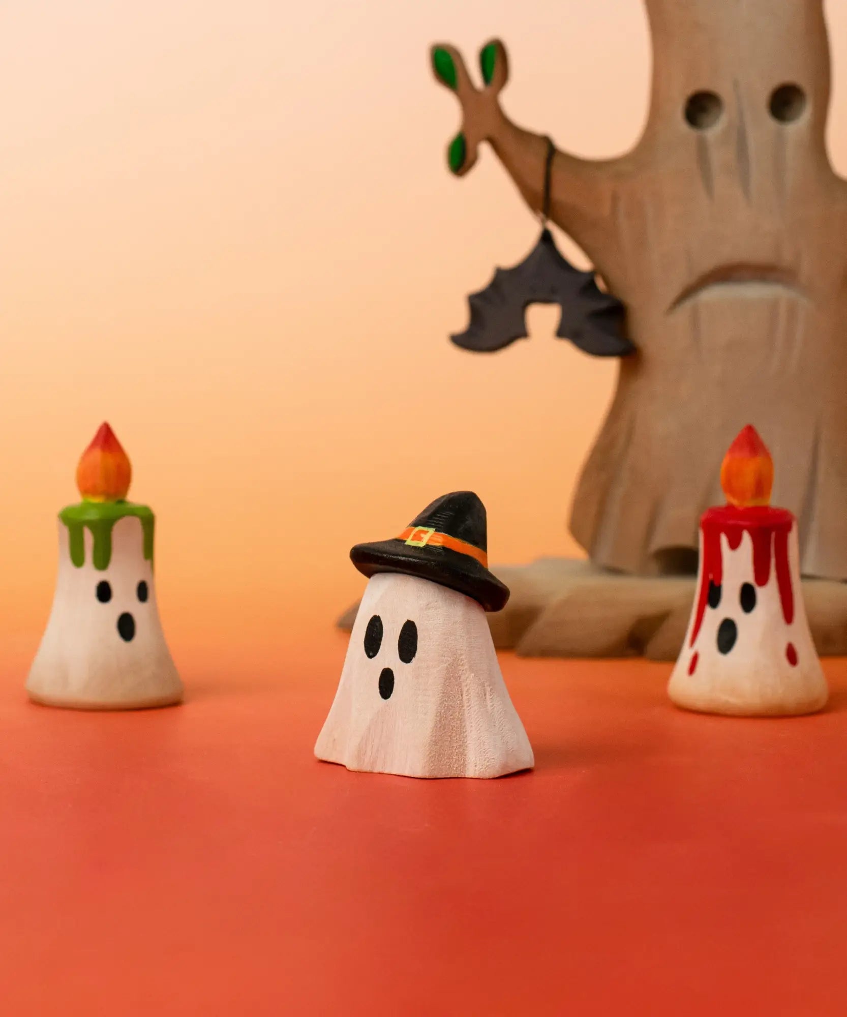 A Bumbu wooden ghost wizard decorative figure standing in front of spooky candles and tree figures 