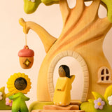 Bumbu wooden golden fairy figure standing in front of a fairy treehouse next to a daisy flower child figure