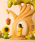 Bumbu wooden golden fairy figure standing in front of a fairy treehouse next to a daisy flower child figure