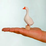 Adult hand holding the Bumbu handcrafted wooden white decorative figure showing size